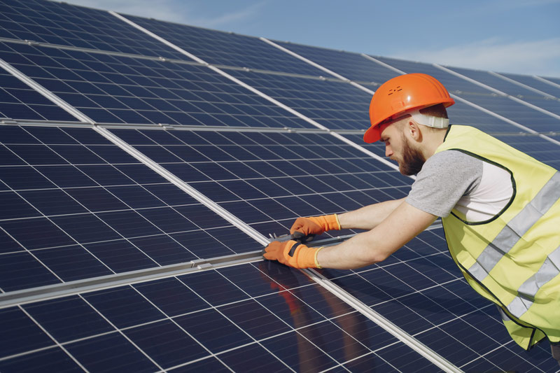 Techniker mit orangem Helm montiert Solarpanele für Energieberatung Hamburg Bausachverständiger